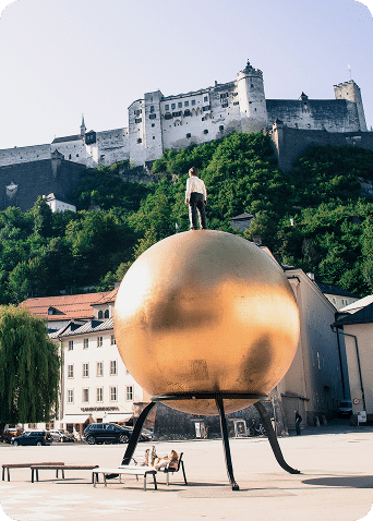Goldene Kugel am Kapitelplatz mit Blick auf die Festung Hohensalzburg an einem sonnigen Tag.