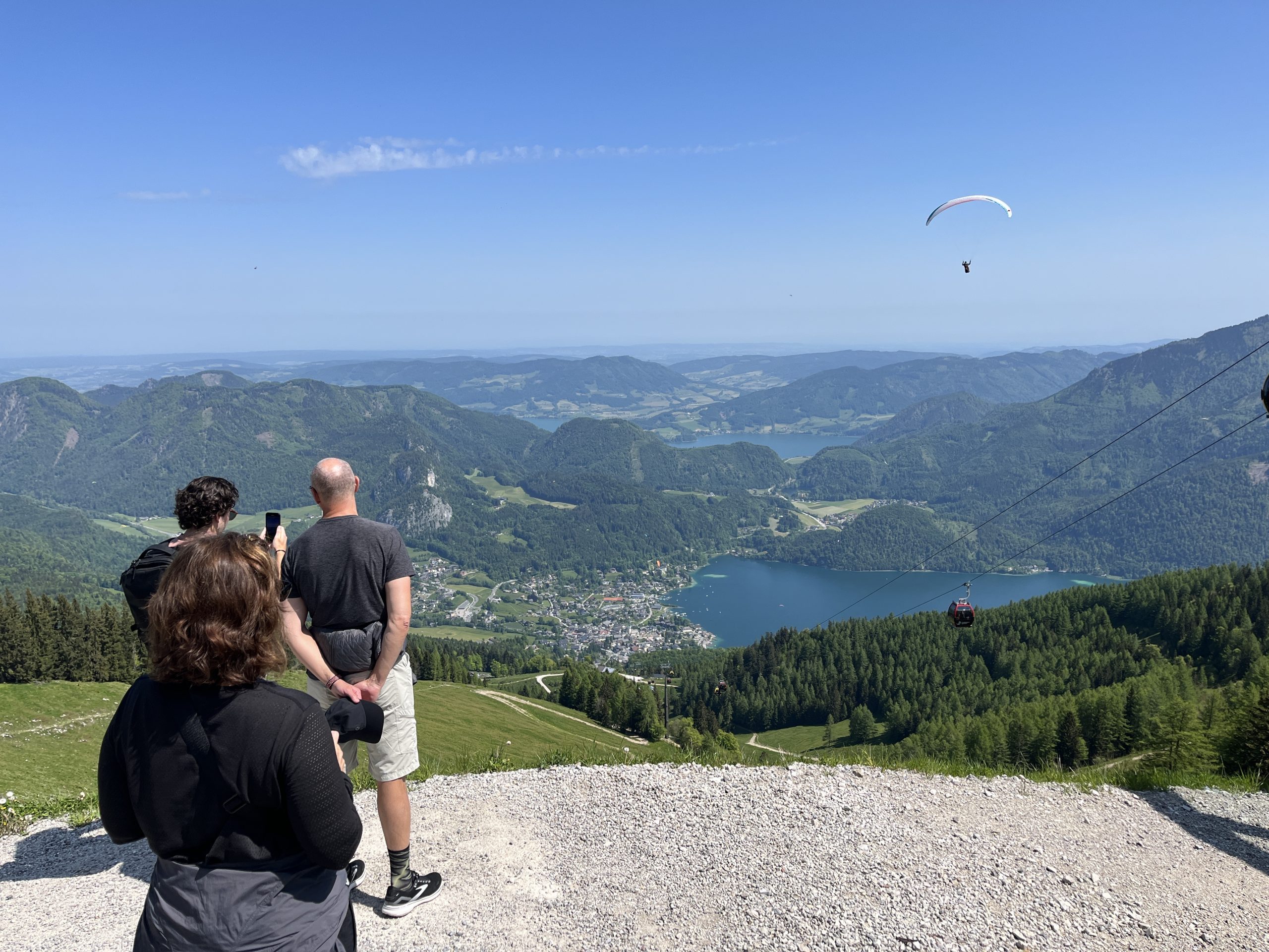Gruppe genießt den Ausblick über das Salzkammergut mit Paragleiter und blauem Himmel.