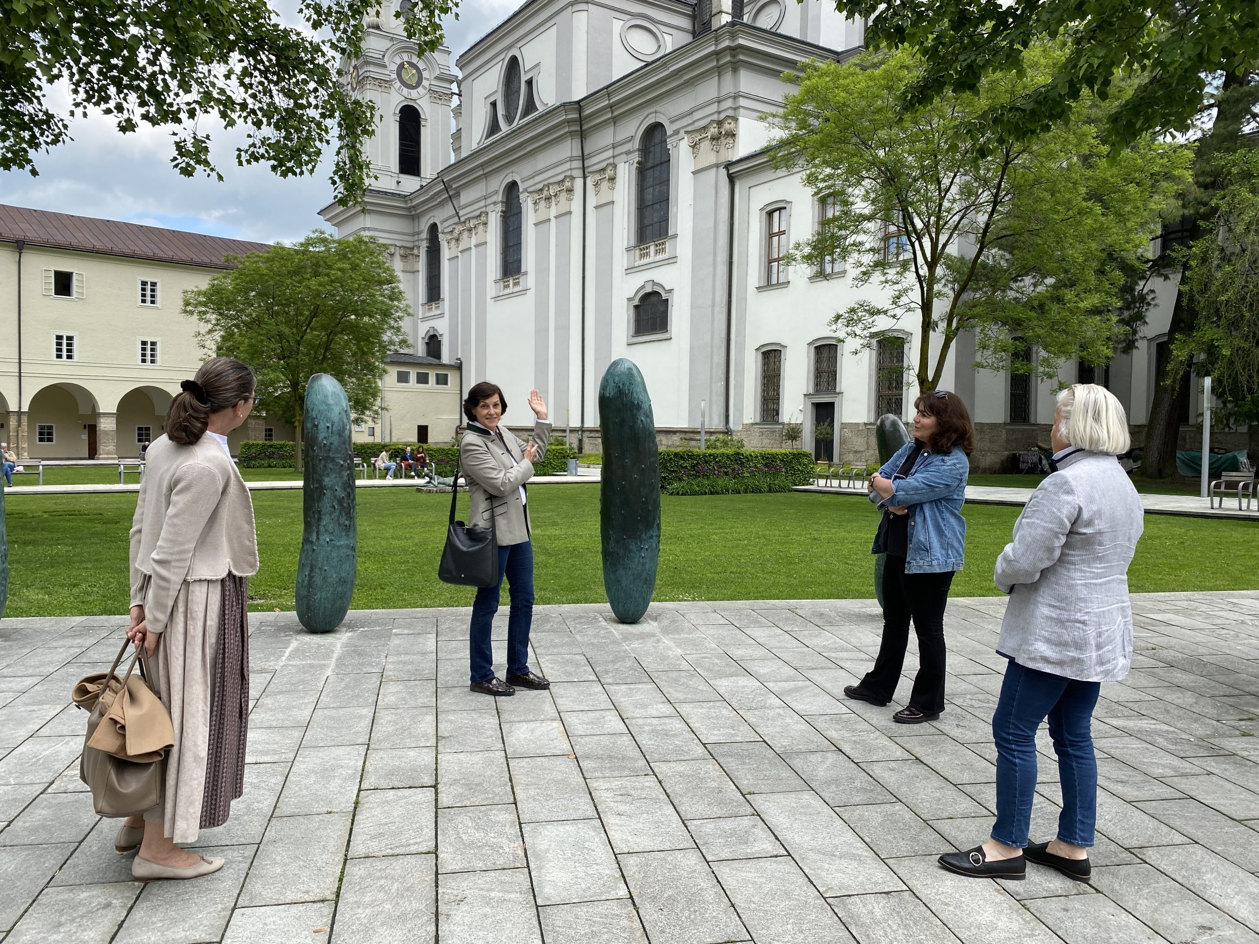 Kleine Gruppe auf Stadtführung vor historischer Kirche in Salzburg mit moderner Kunst im Freien.