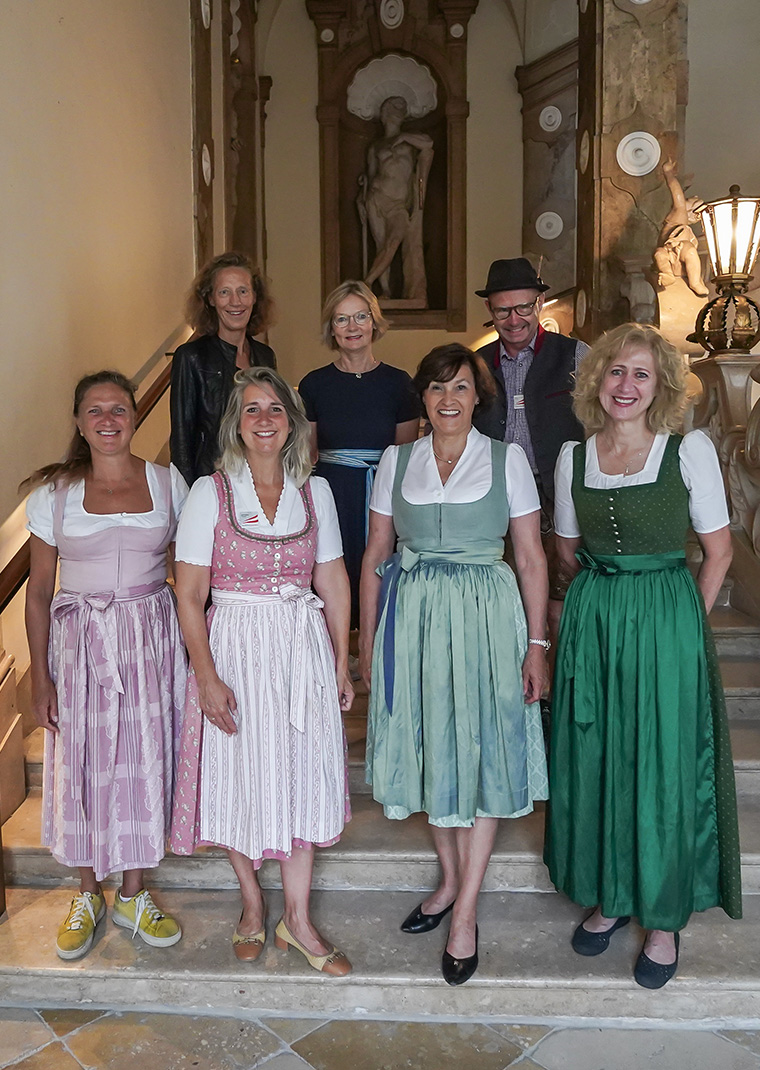 Das Team von Salzburg Experience steht auf einer Treppe in traditioneller Kleidung und lächelt in die Kamera.